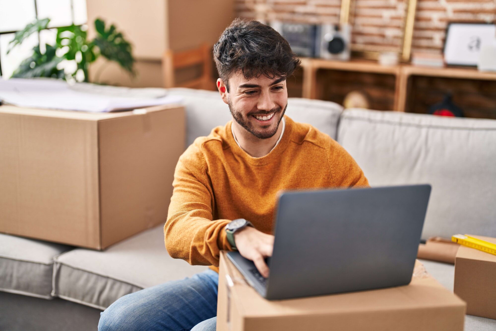 Young man moving into new home on laptop