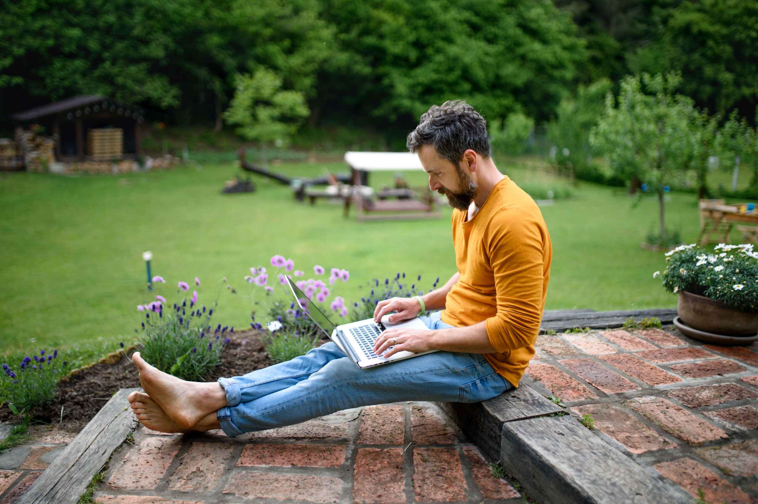 Man sits in garden using laptop