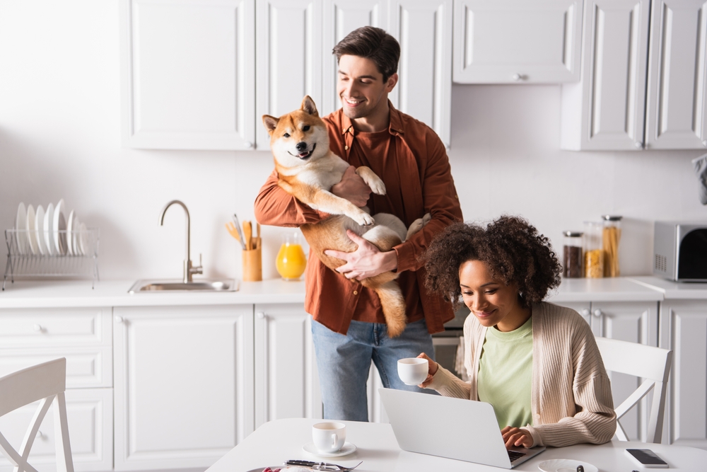 Young couple holding a dog in their kitchen