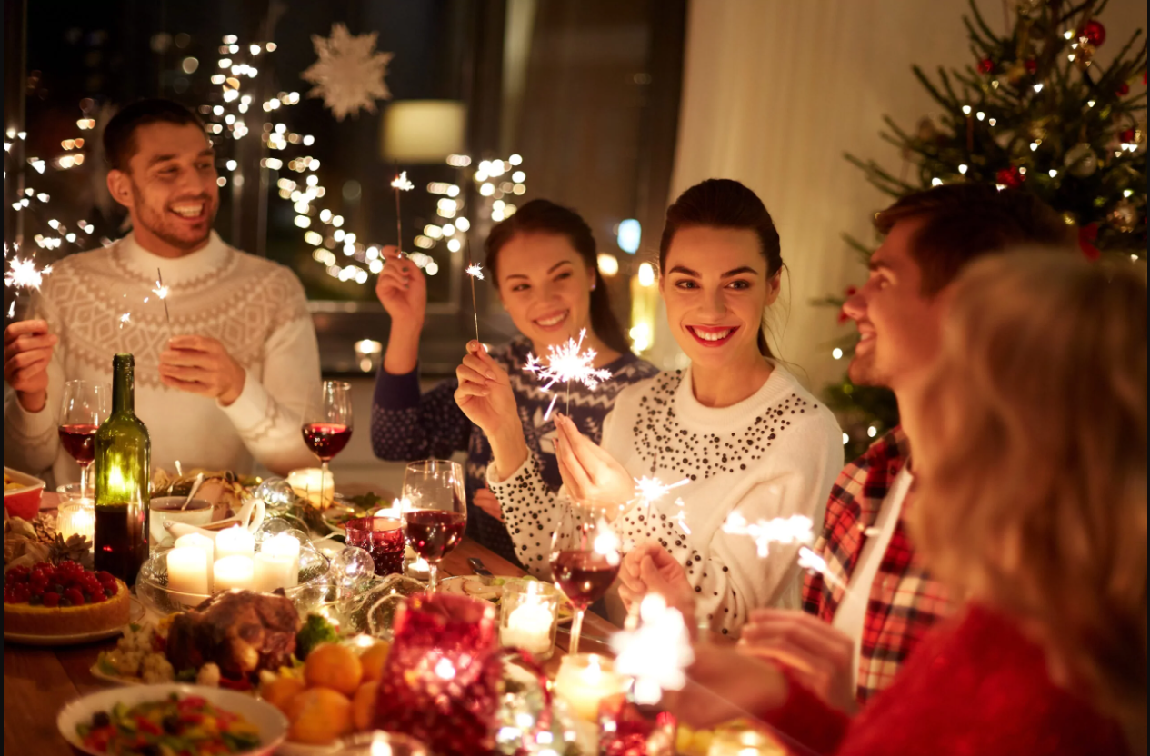 Young group celebrate with sparklers at the Christmas dining table