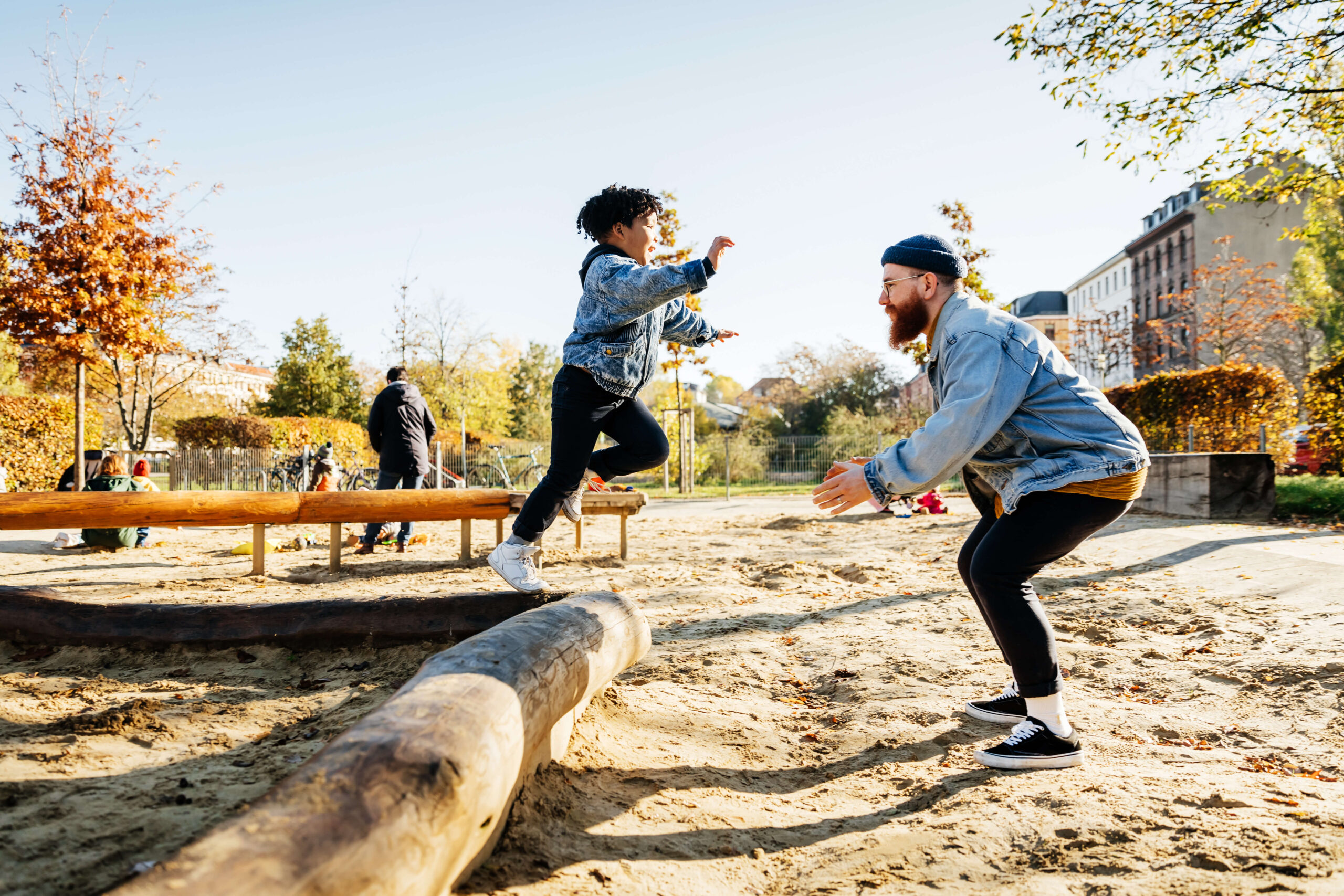 Young boy jumps into father's arms in playground