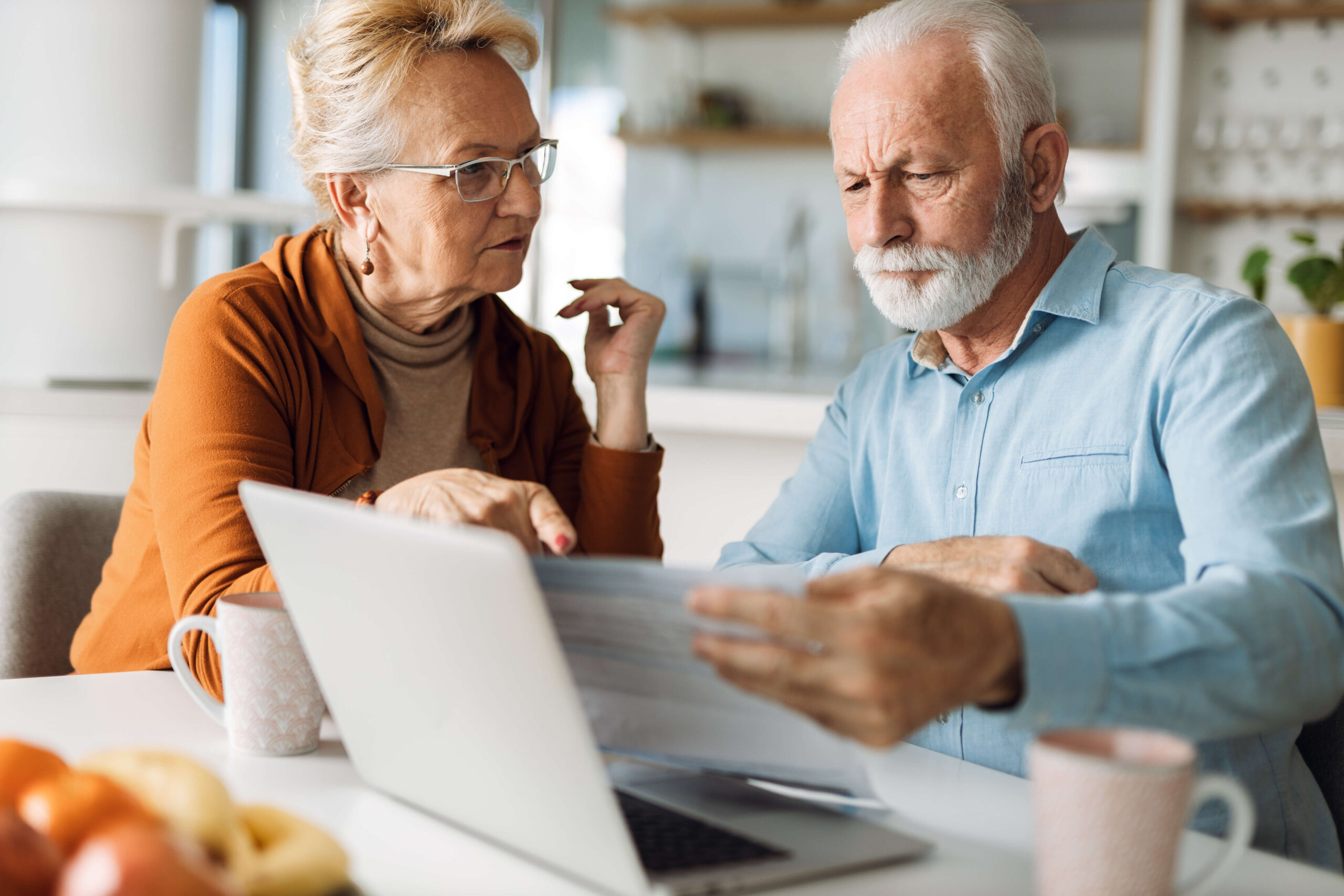 Mature couple looking at finances in kitchen tense