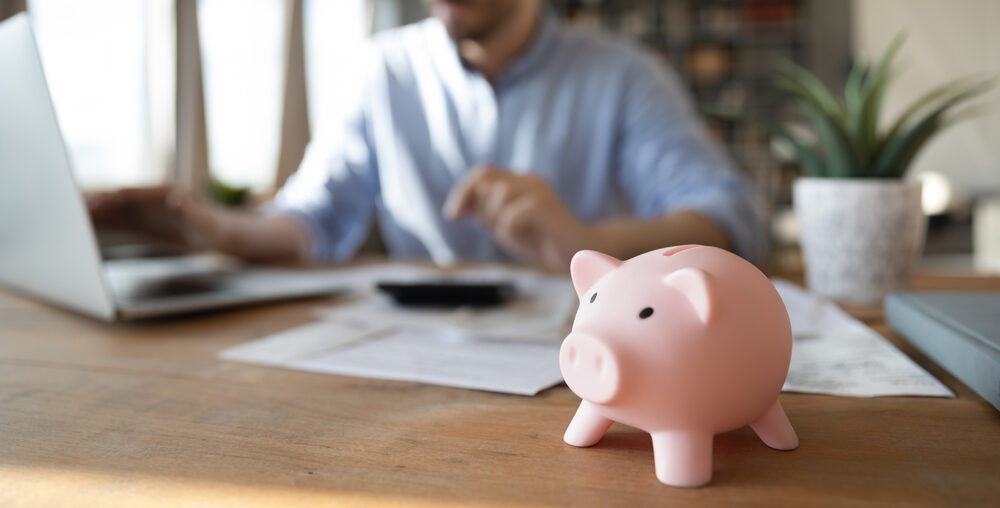 Piggy bank with man on laptop in the background