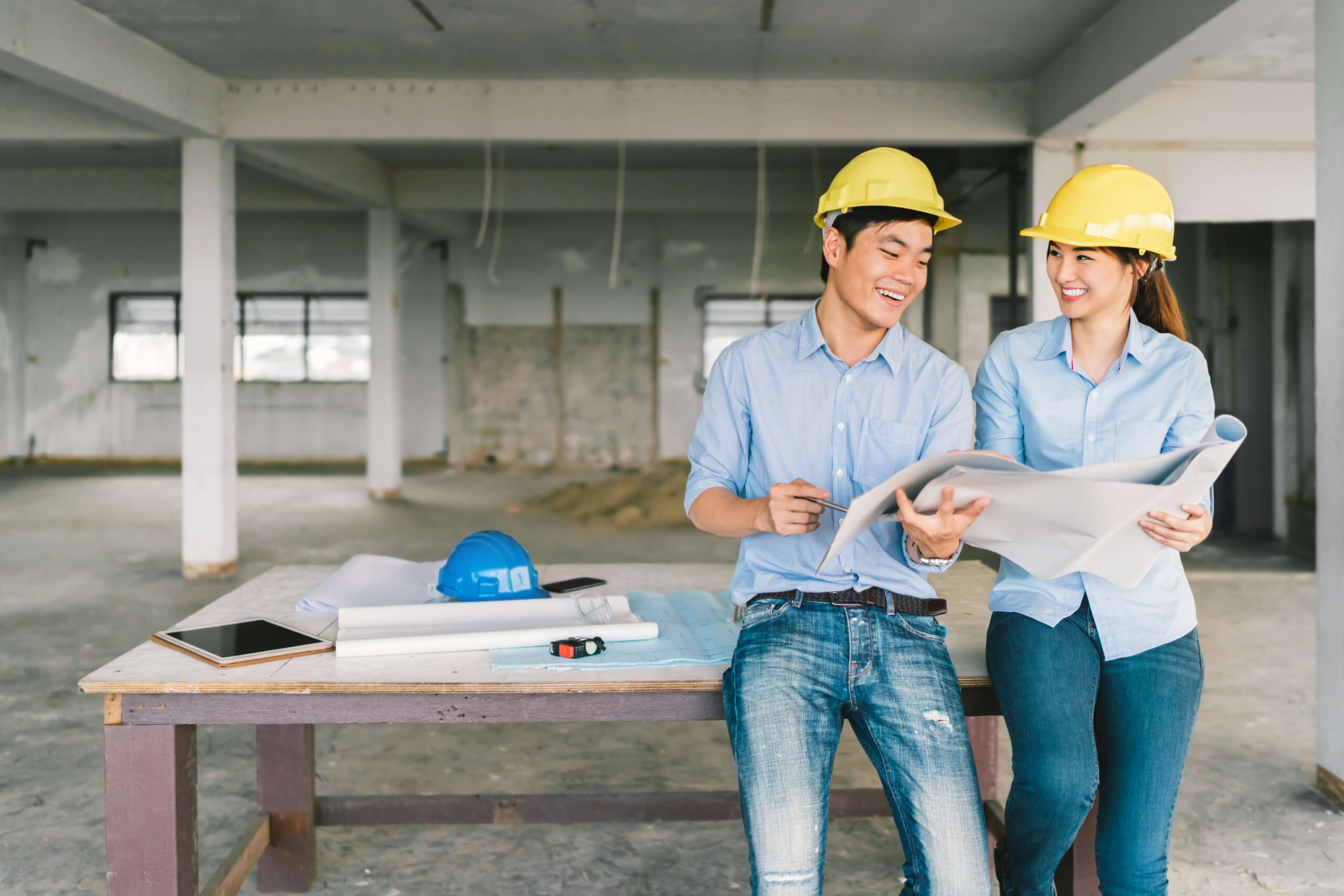 Young couple in hardhats on site