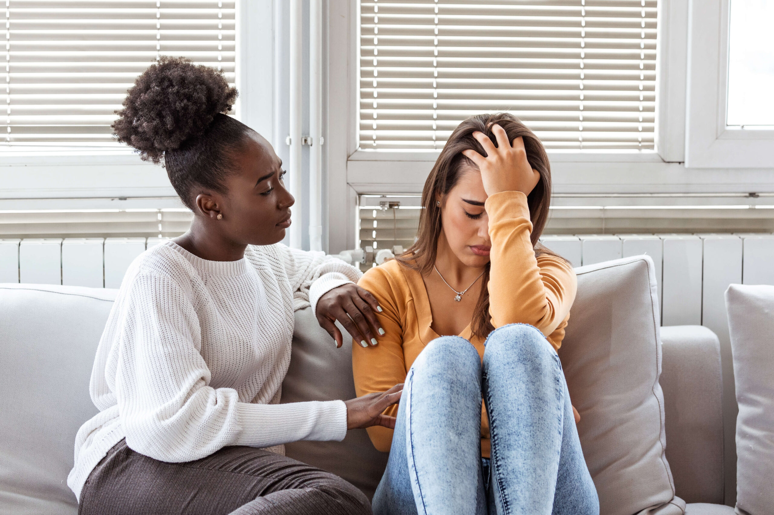 Young woman sad, comforted by a friend