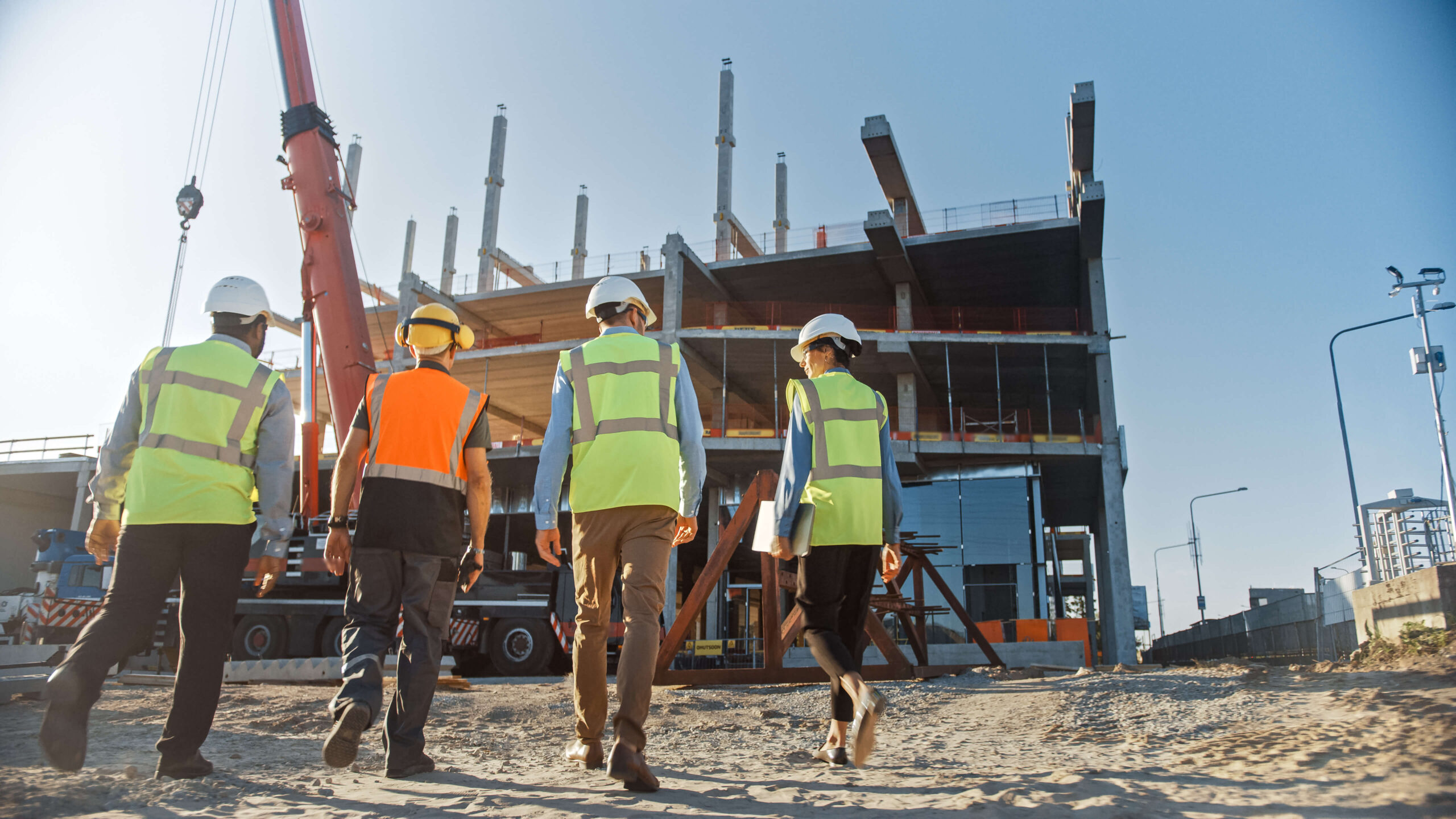 Group of construction workers walk across building site