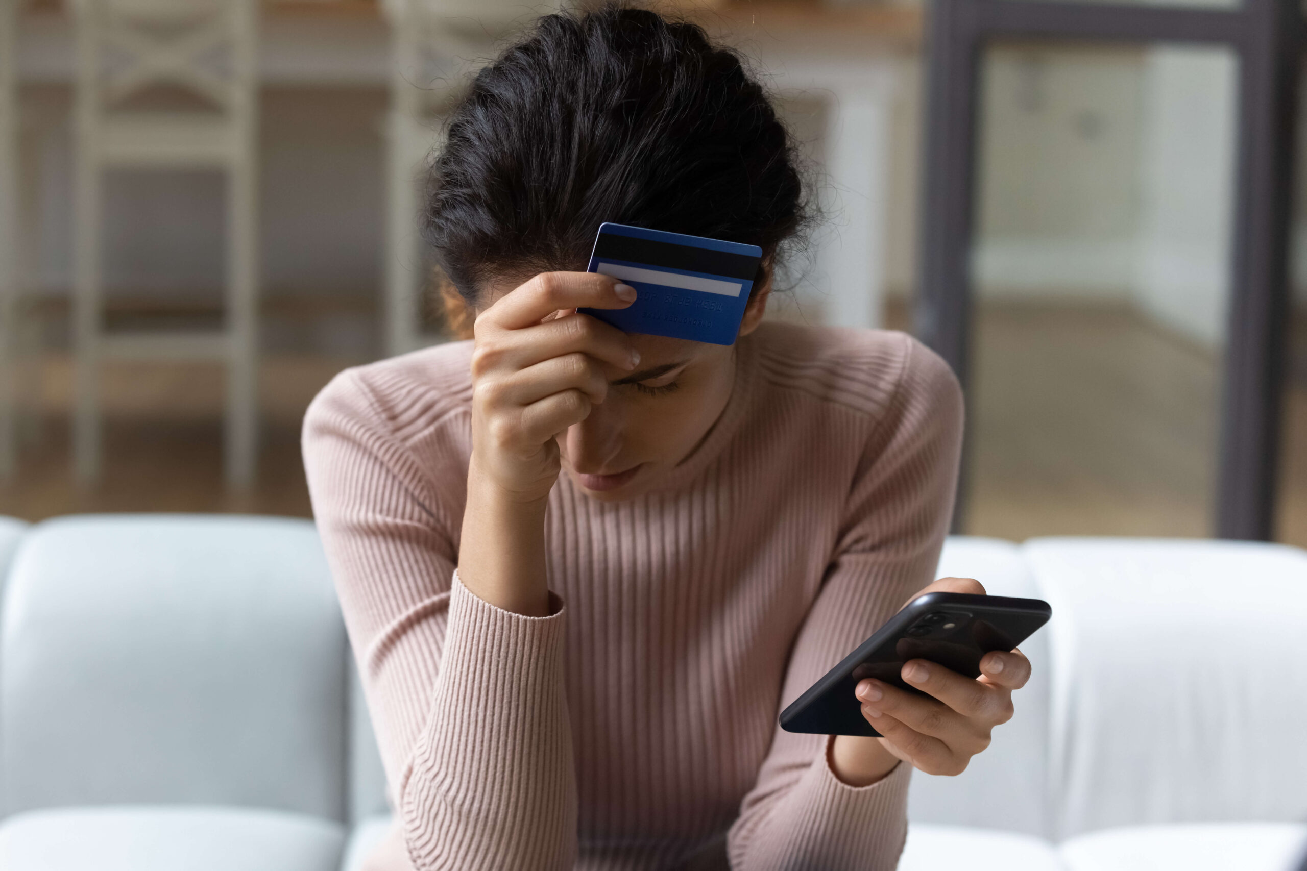 Women worries with credit card and phone in hand