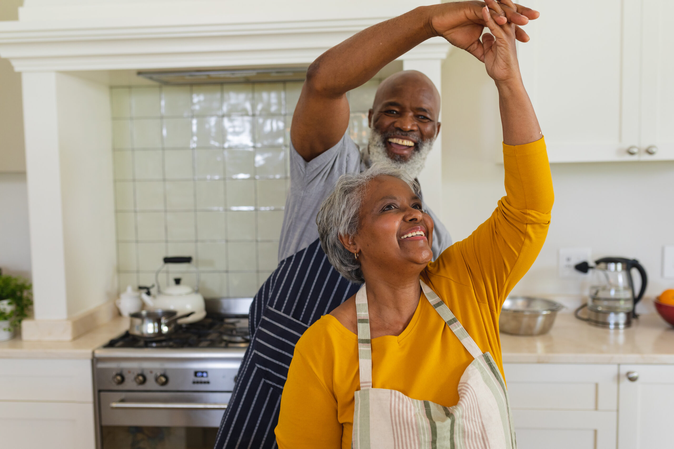 Mature black couple happily dancing in the kitchen