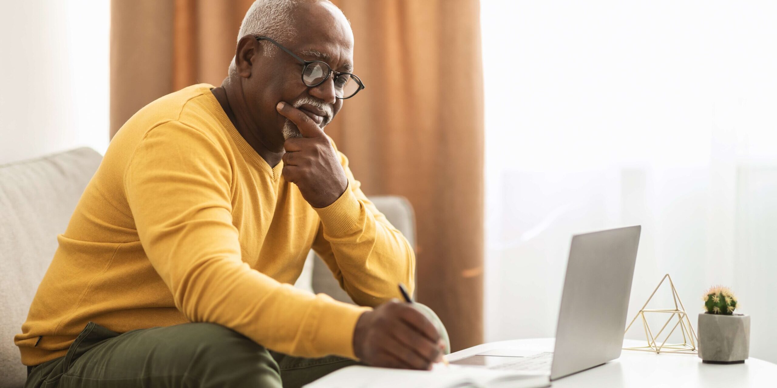 Man thinking, with pen and laptop