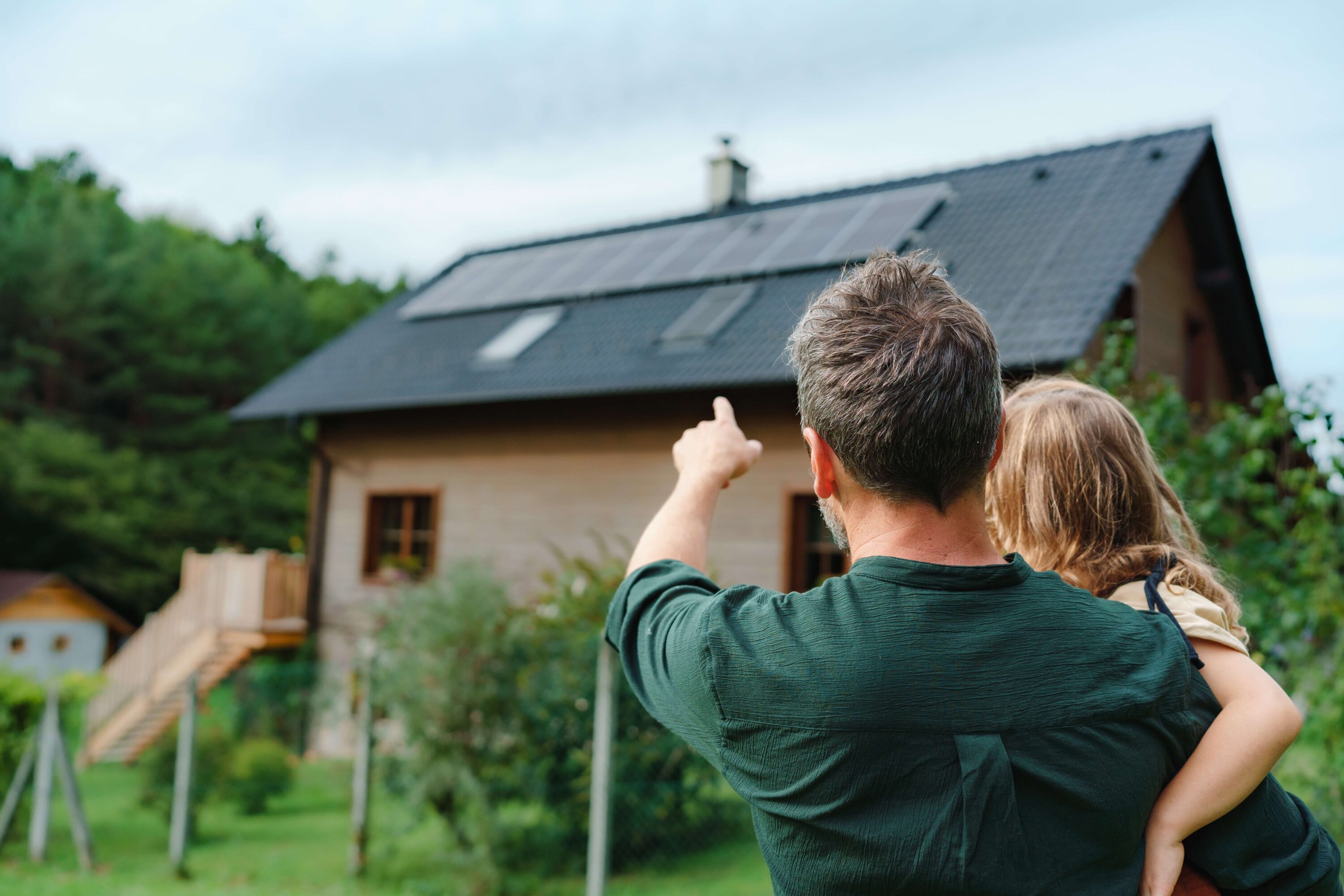 Man and daughter look at solar panels on a house