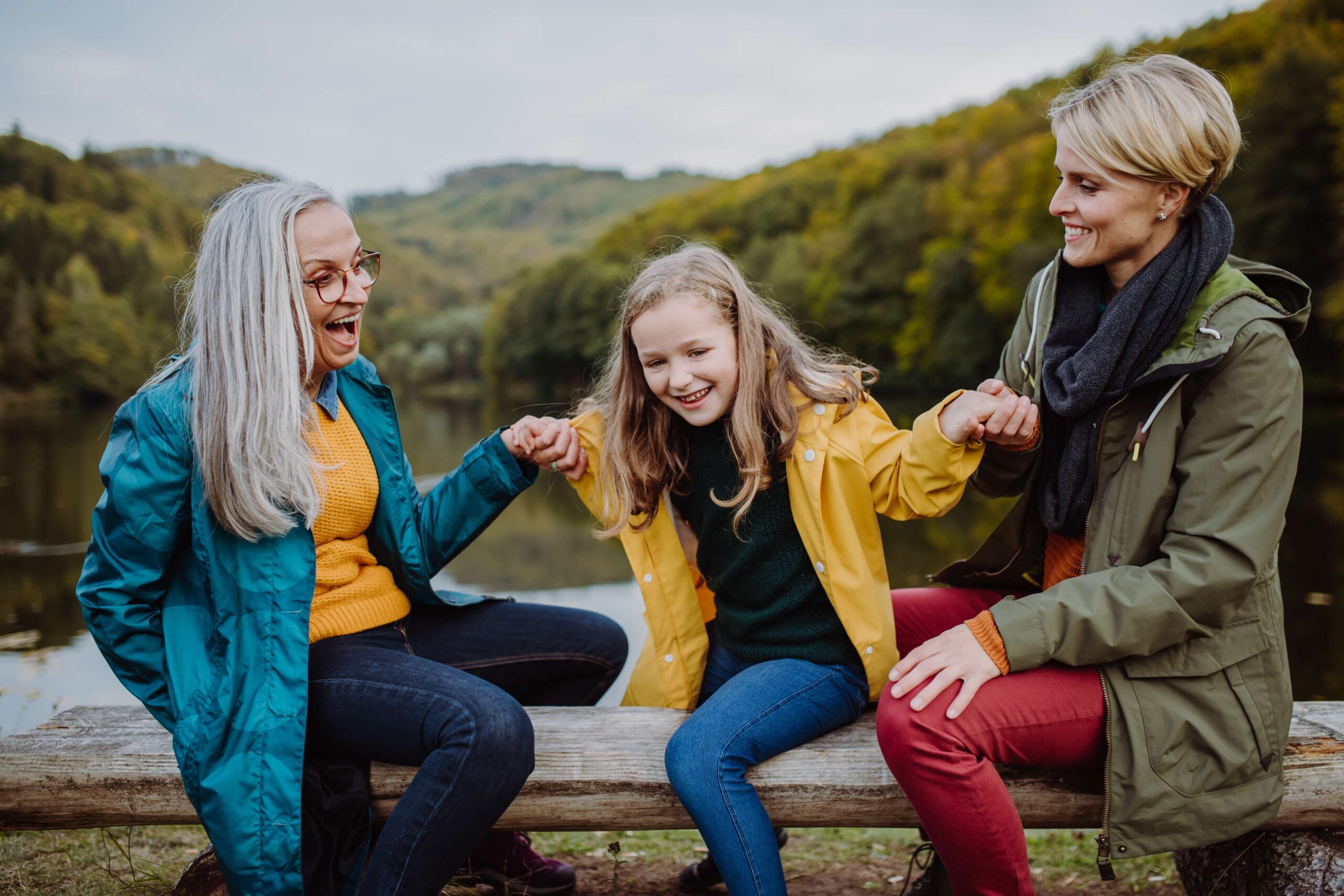 Grandmother, granddaughter and mum on bench outside happy