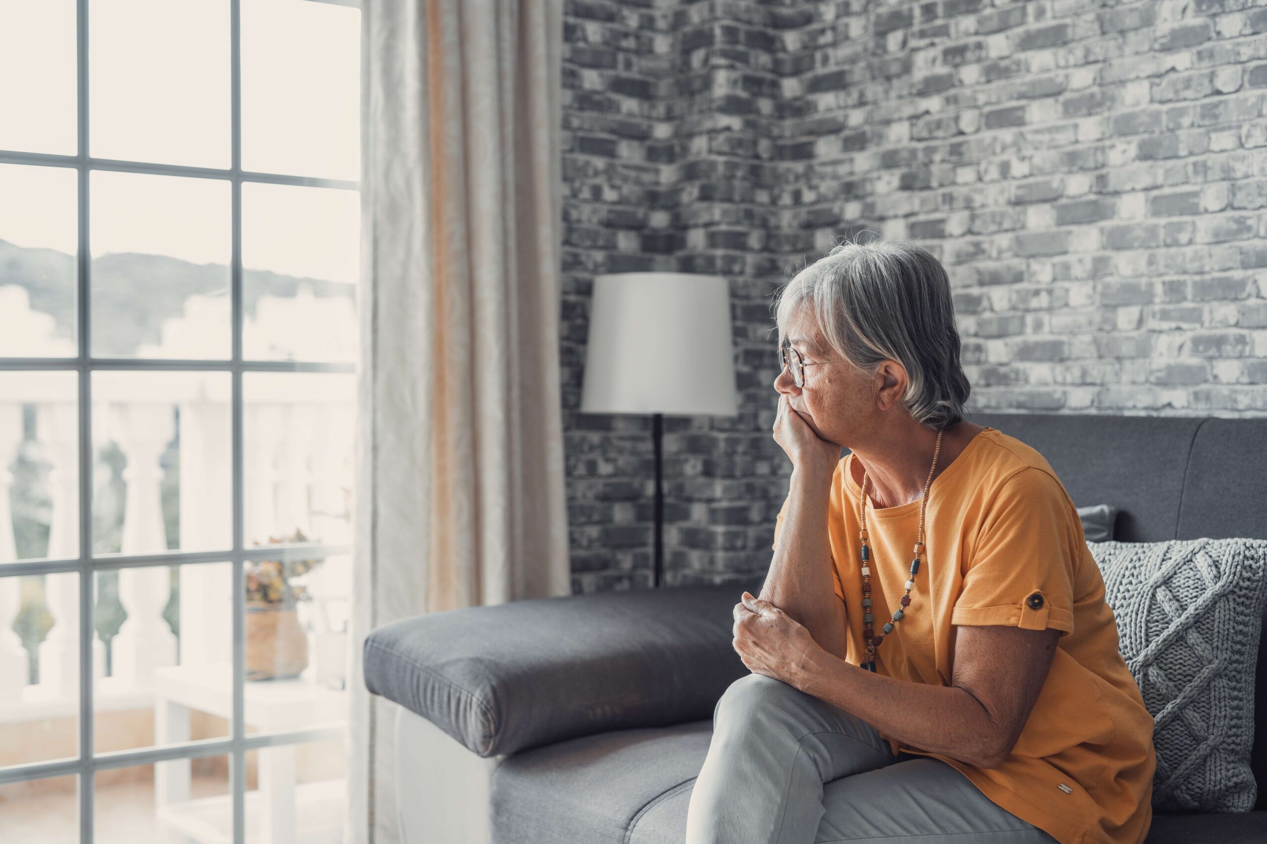 Concerned mature lady looking out of window