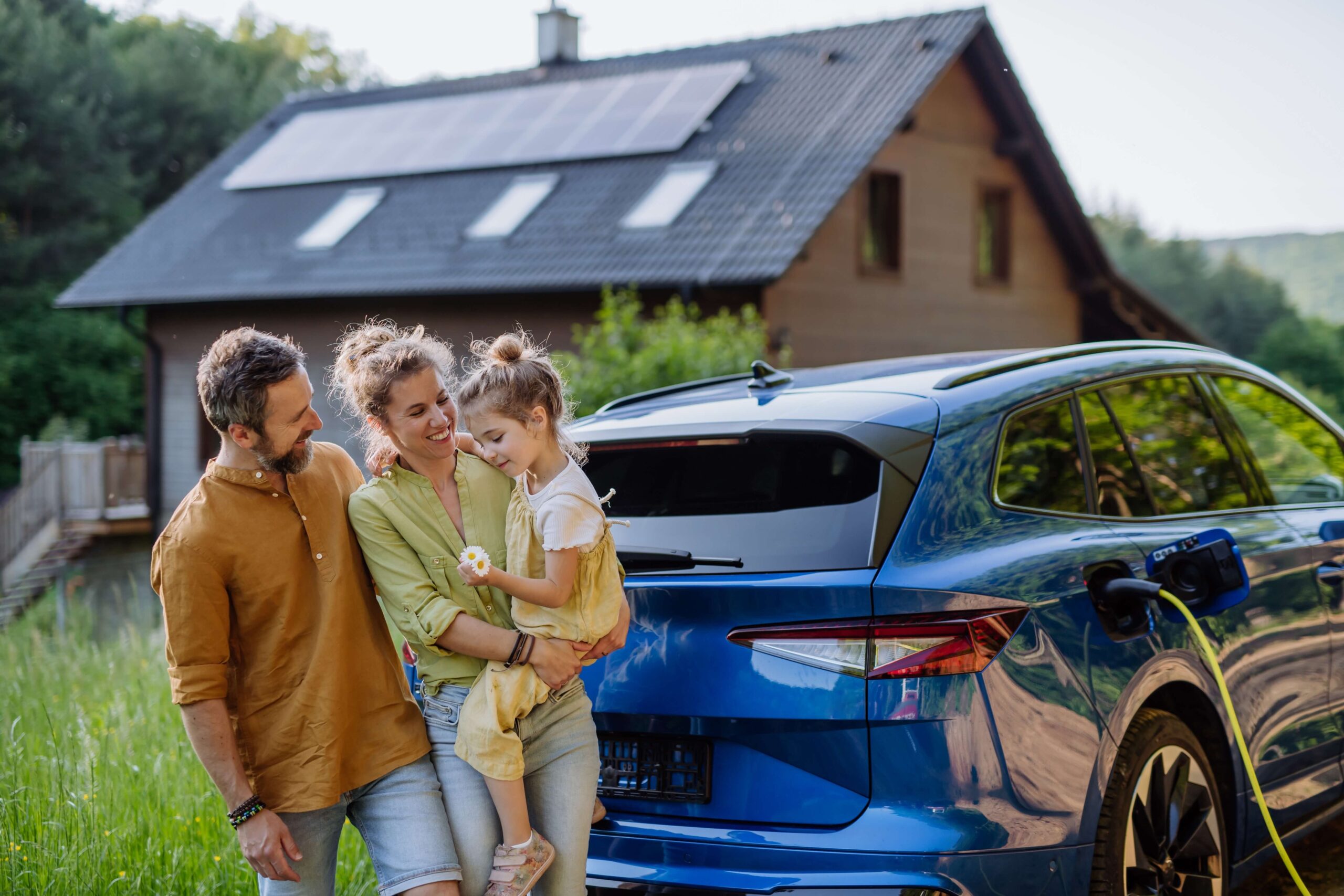 Young family with daughter outside home near car