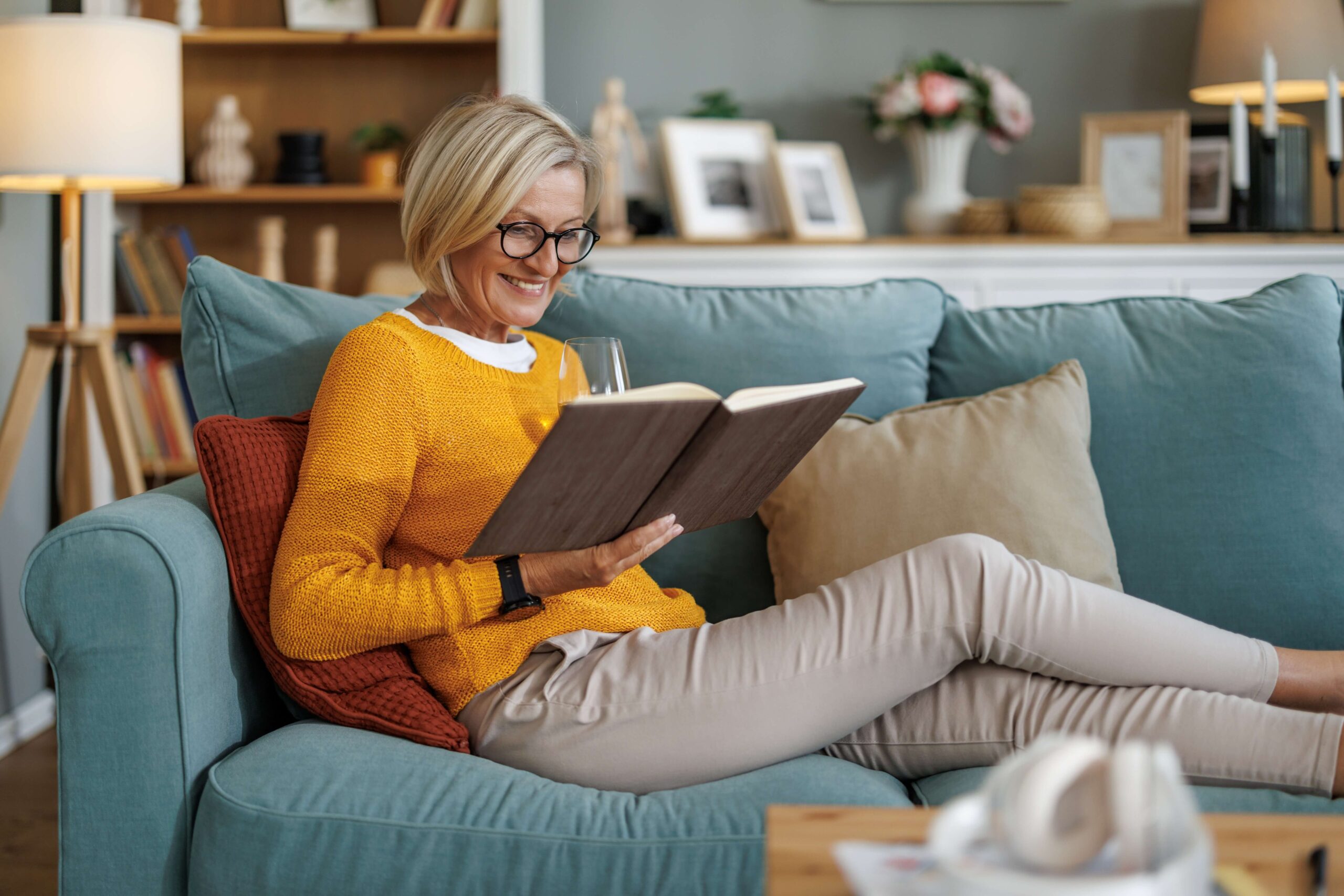 Mature woman reading book on sofa