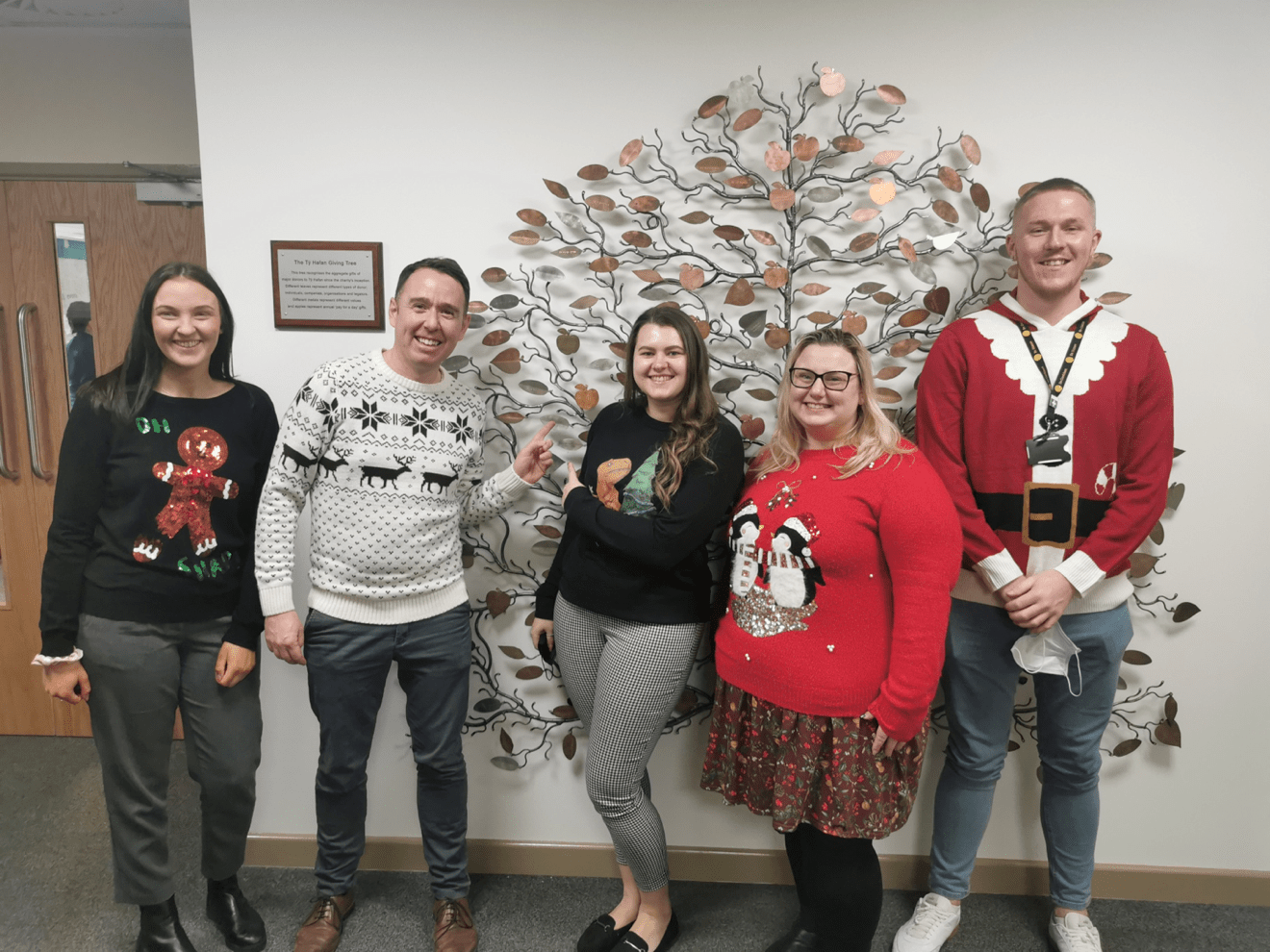 five of the Hodge team wear festive jumpers with the tree