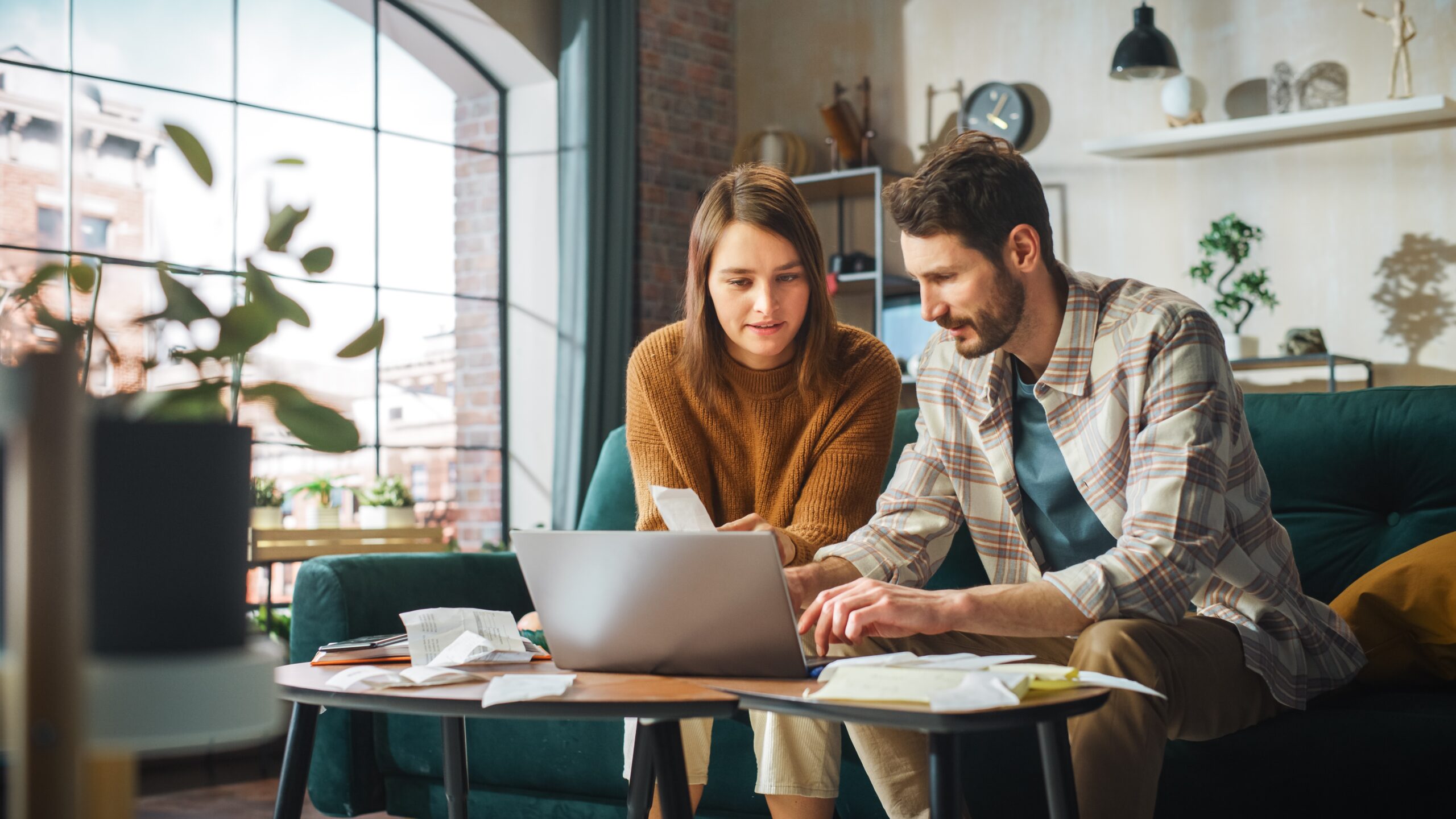 Young couple review receipts and look at laptop