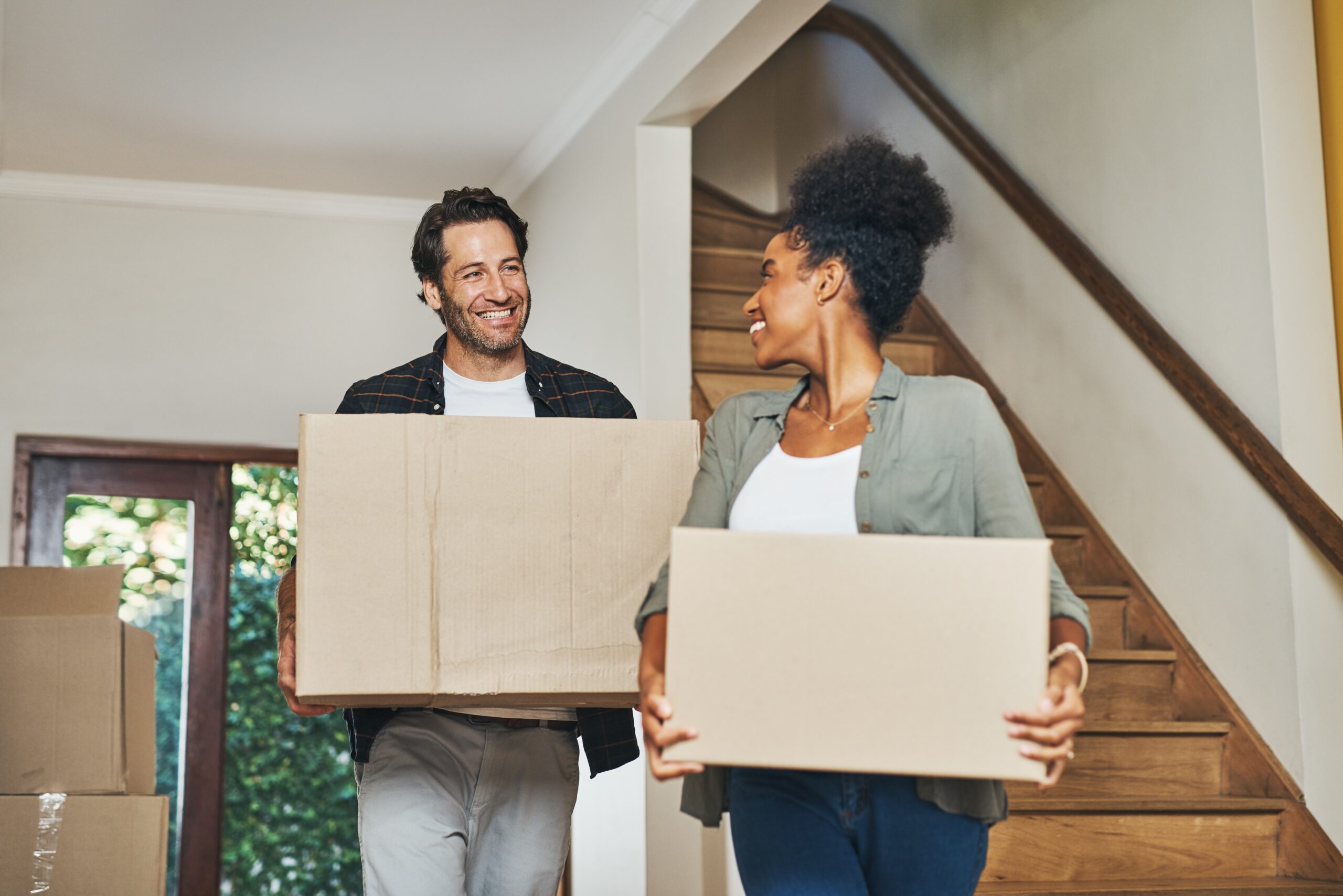 A young couple carrying boxes into their new home