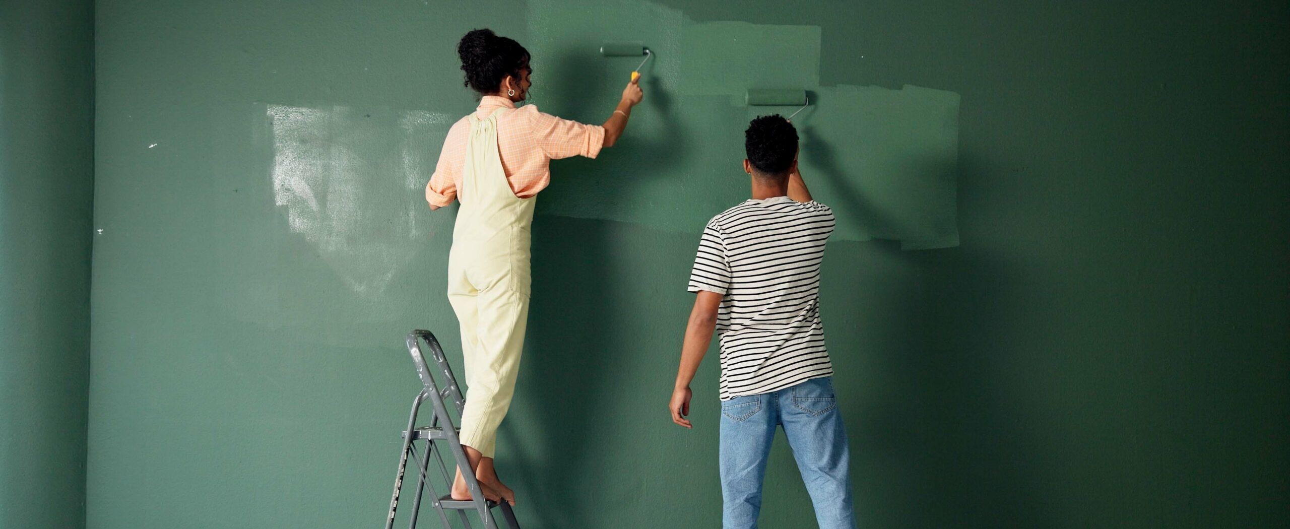 Couple redecorating their home, painting the walls a fresh green colour
