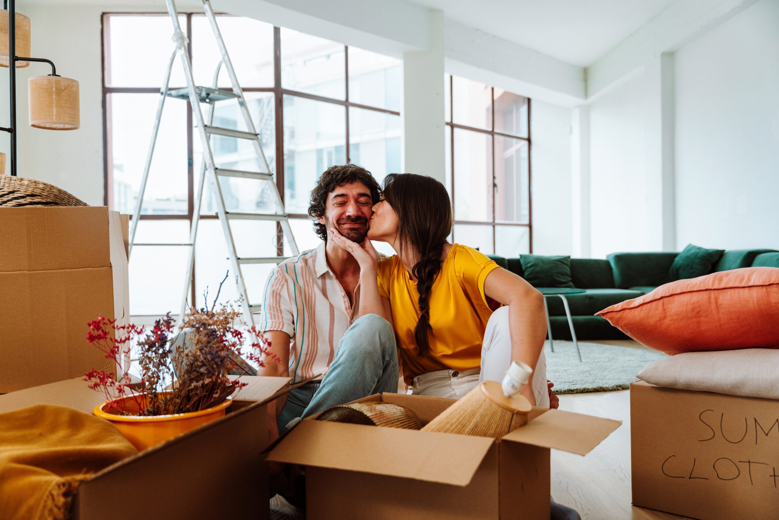 Young couple unpacking box in a house share a kiss