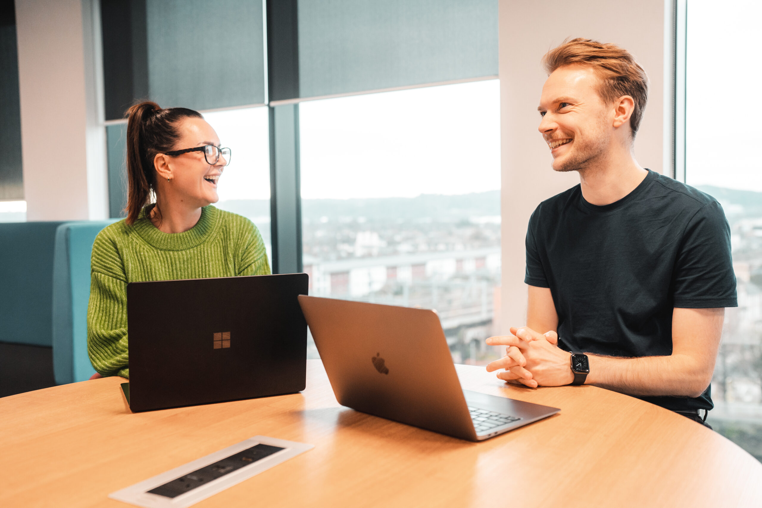 Two colleagues sat on chairs laughing