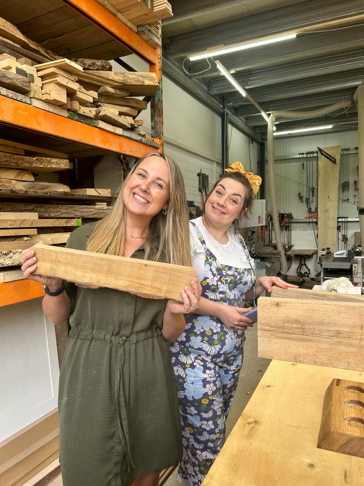 Two colleagues smiling whilst holding a piece of wood
