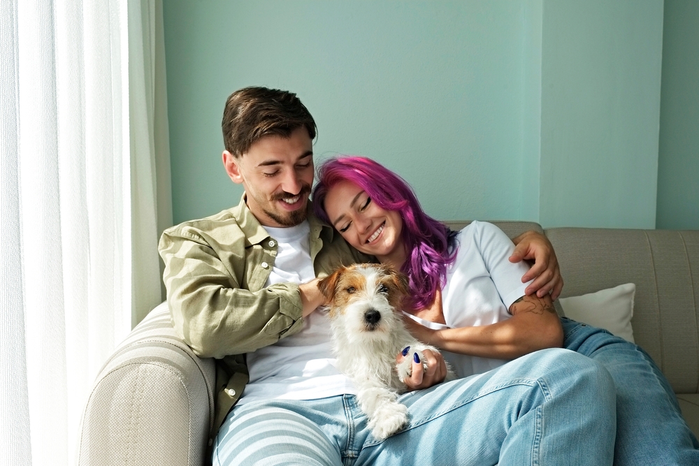 Couple smiling on the sofa with their dog