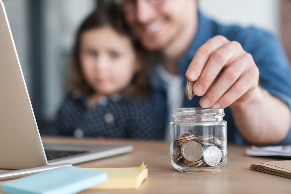 A man and his daughter putting a coin into a jar