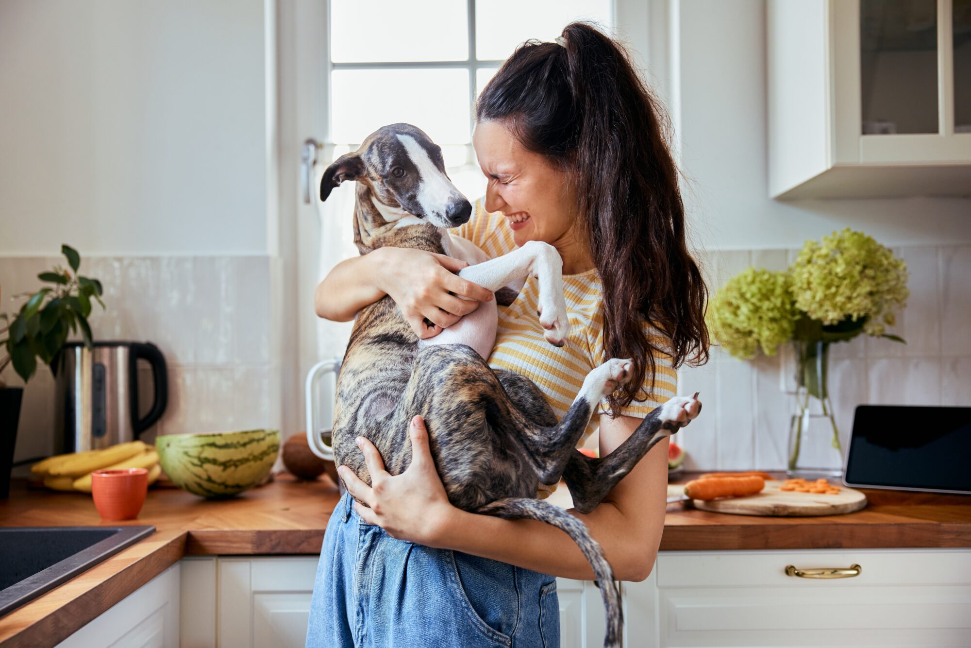 Joyful woman smiles and cuddles dog
