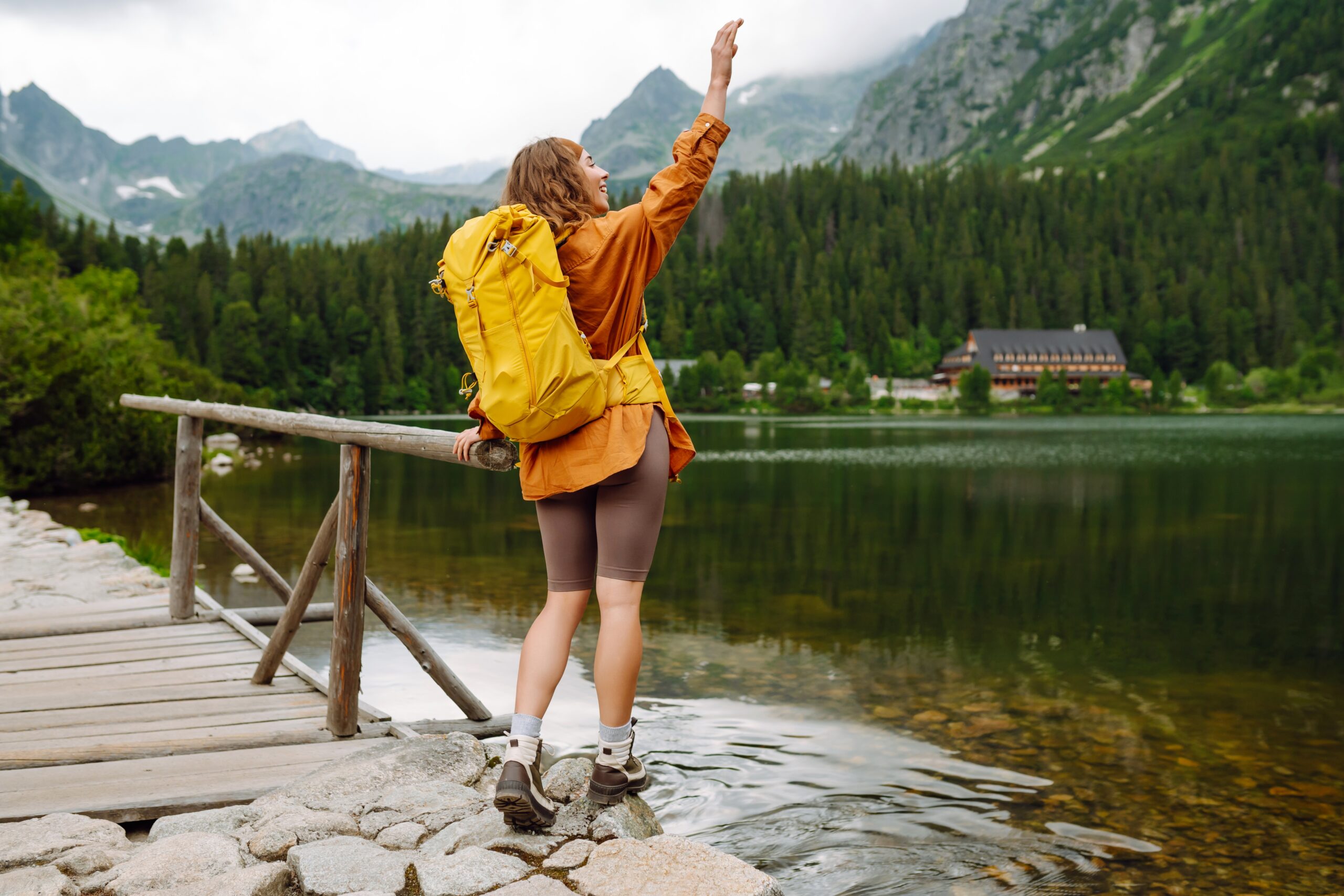 A woman with a yellow backpack next to a lake.