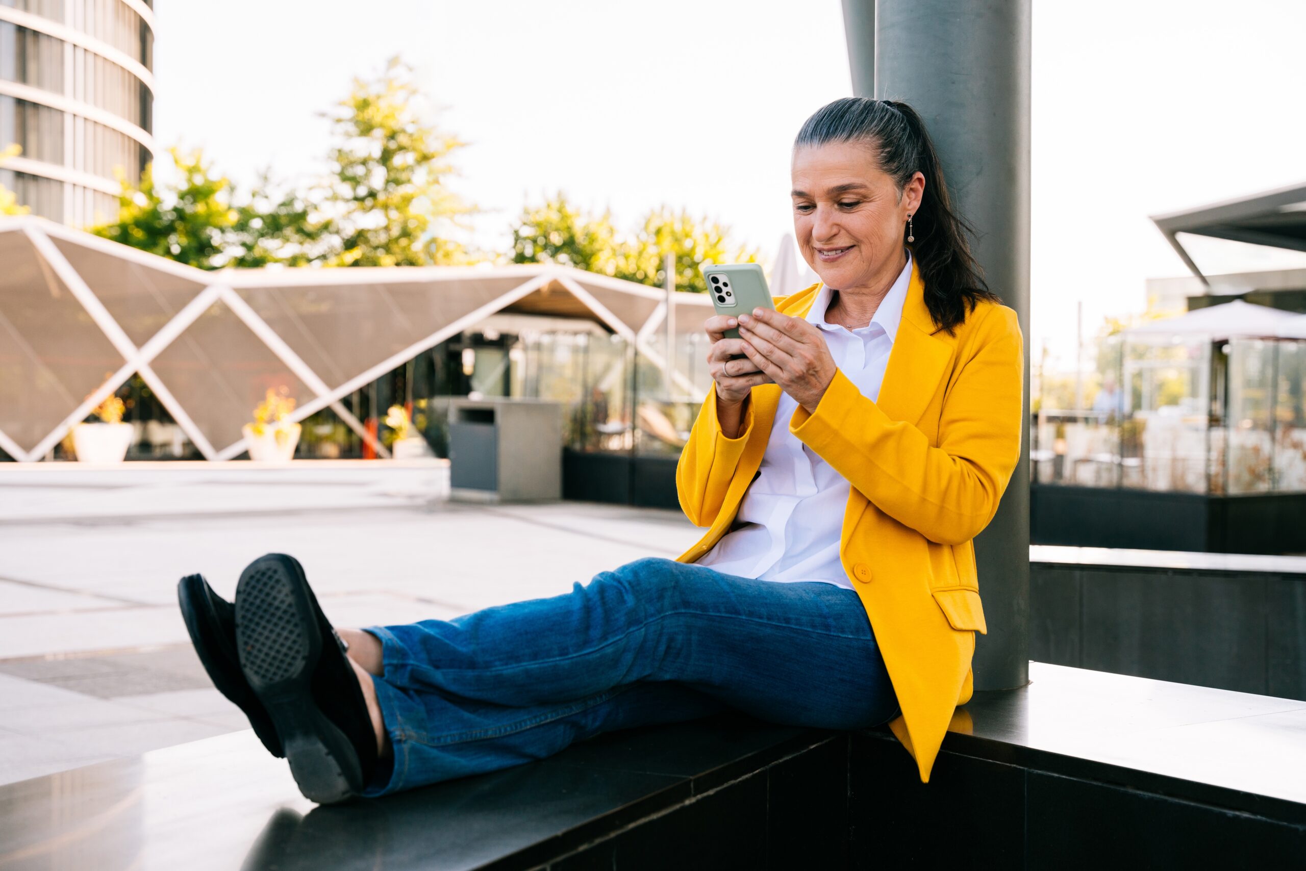 A woman sat with her feet up and looking at her phone.