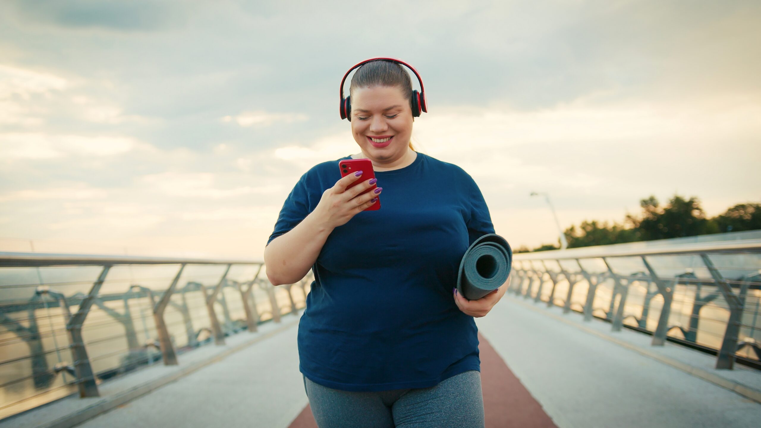 A woman walking and smiling at her phone.