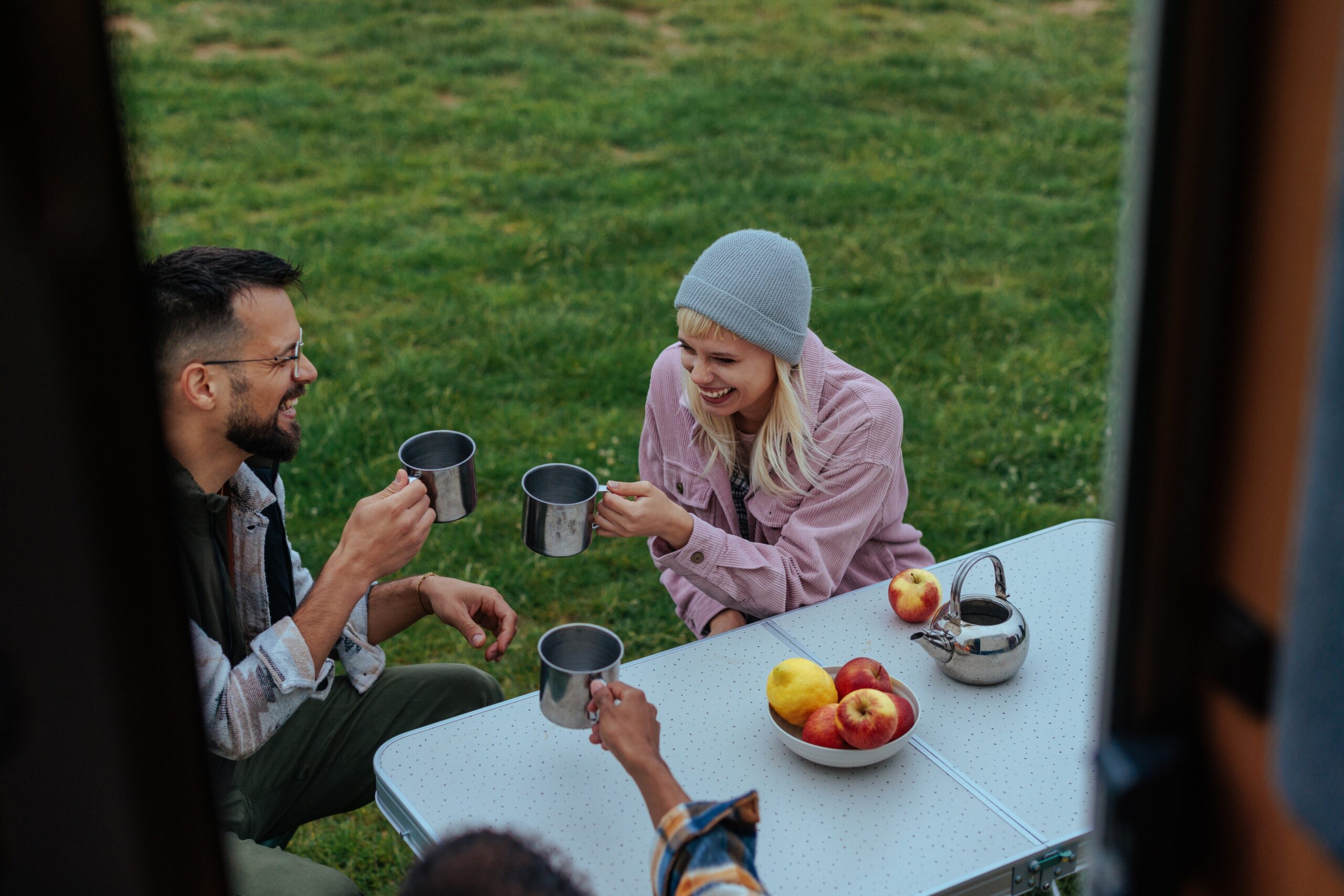 A man and a woman smiling whilst drinking from mugs.