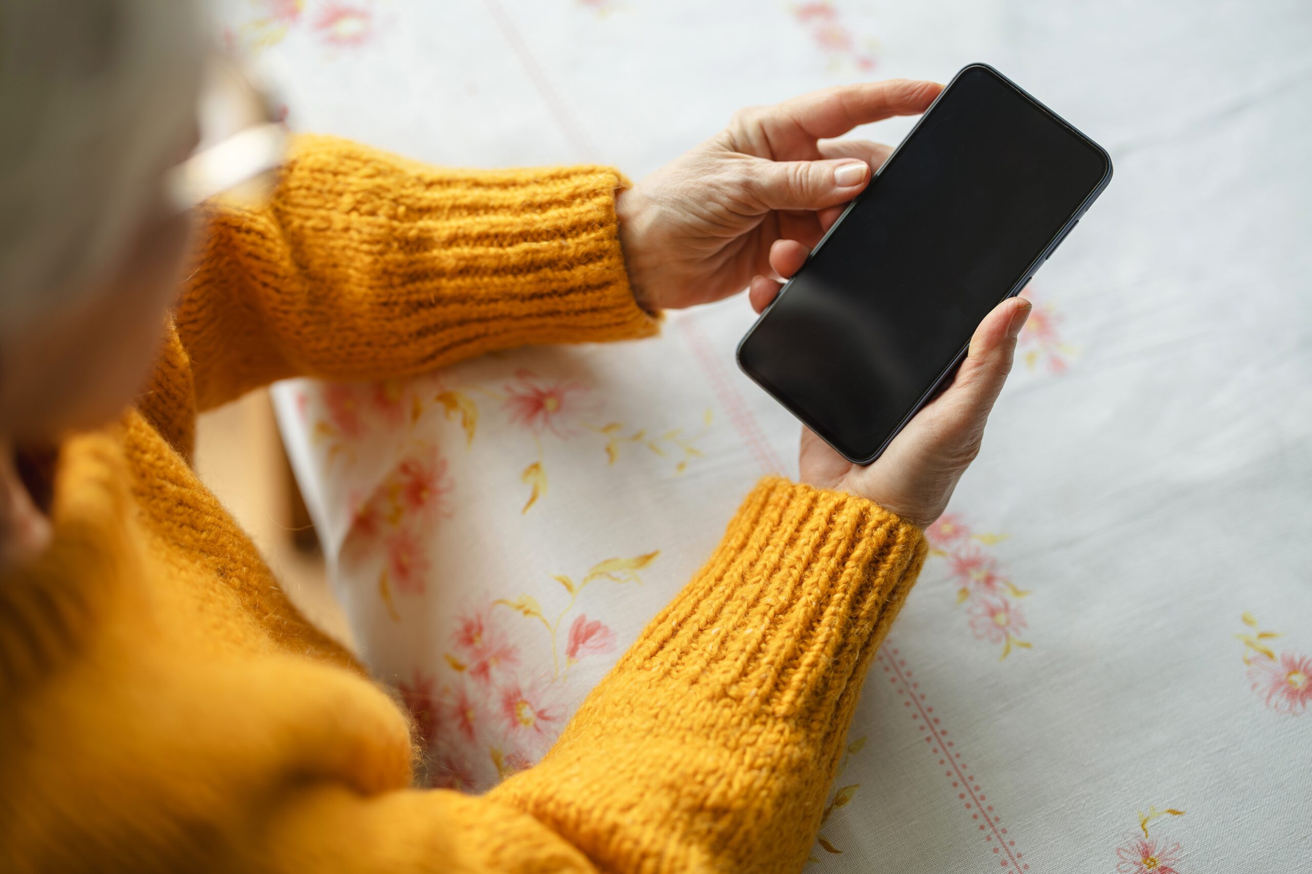 A person in a yellow jumper looking at their phone.